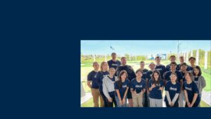 A group of people in navy t-shirts at a Top Golf range