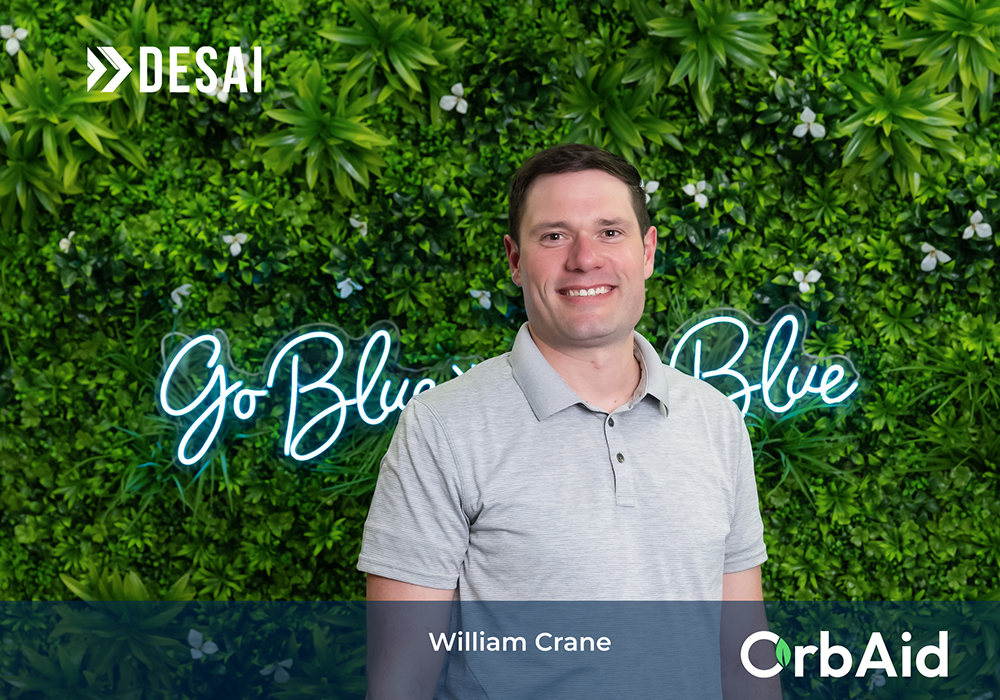 OrbAid founder Bill Crane standing against a wall of greenery.